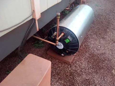 Geyser with new copper pipes on a stand outside a building